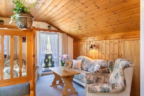 En inredning med trädetaljer, en soffa, ett bord och en hängande växt.