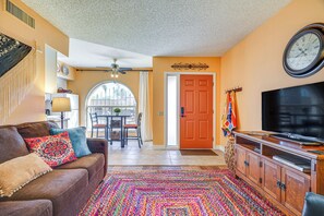 A living room with a brown leather couch, colorful rug, wooden cabinet, and a television. - Charming Green Valley Townhome w/ Community Pool! (Green Valley)