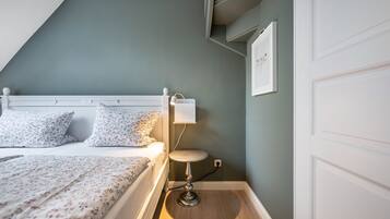 Une chambre à coucher avec un lit, une table de chevet, une lampe et un tableau accroché au mur.