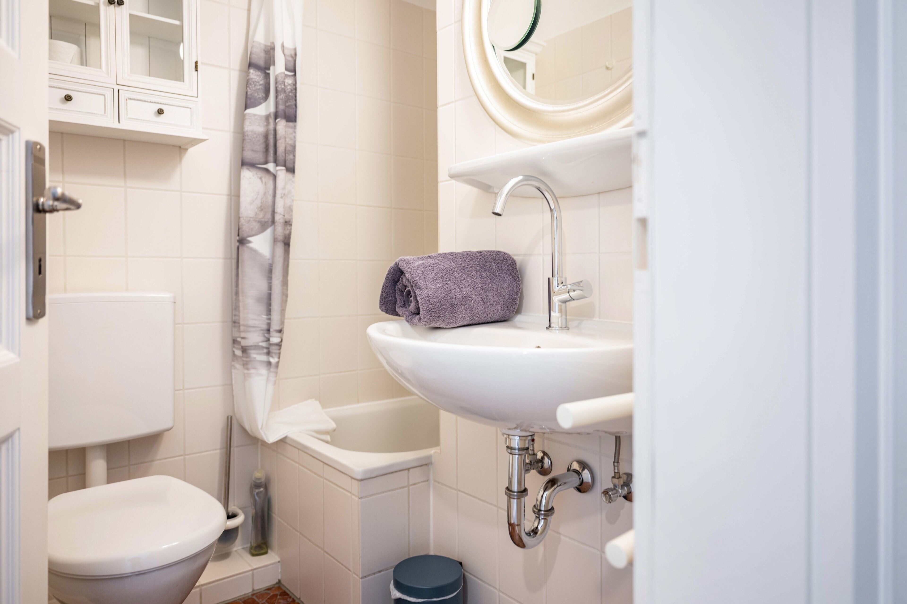 Une salle de bain équipée de toilettes, d’une baignoire, d’un lavabo et d’une serviette posée sur le lavabo.