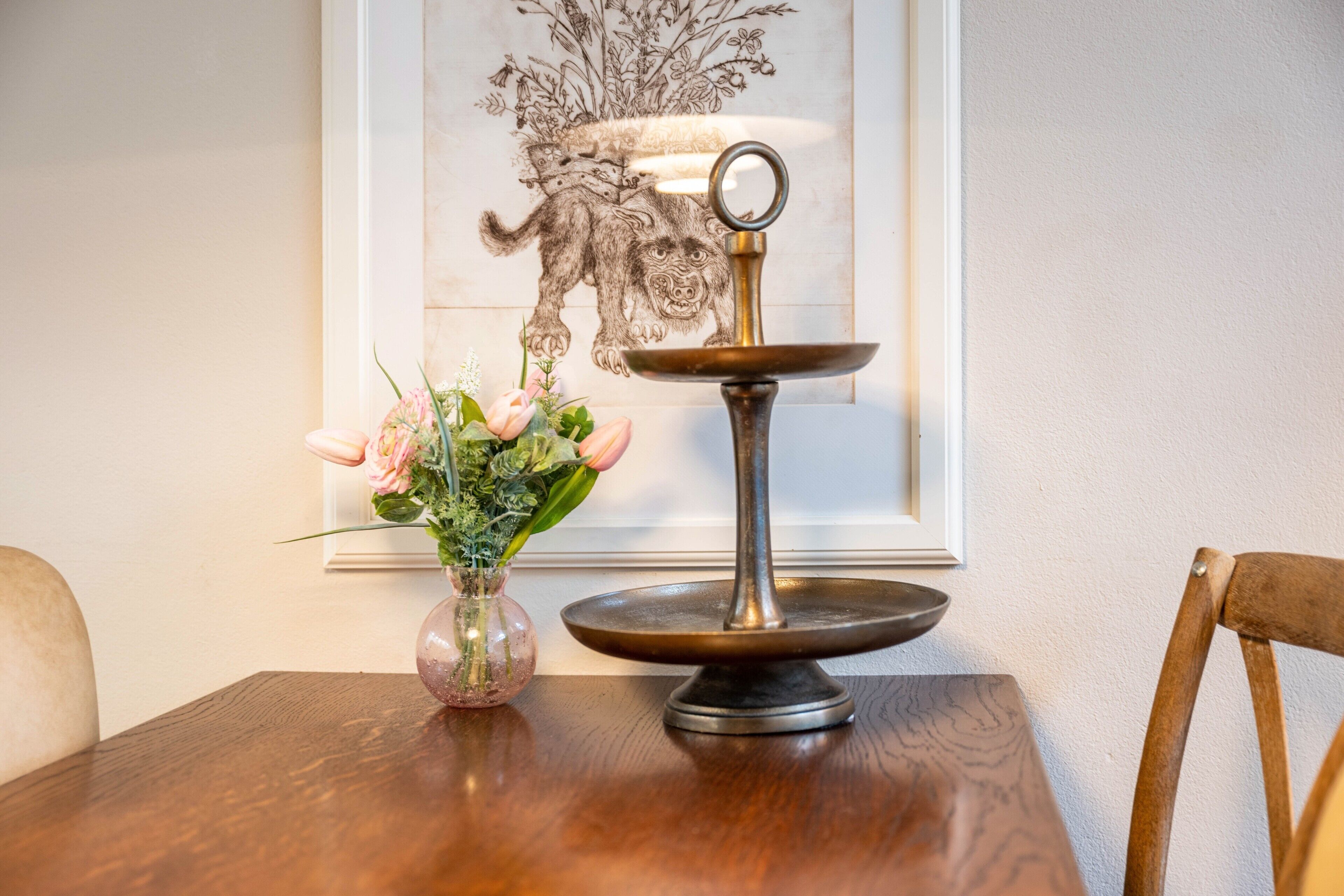 A wooden table with a vase of flowers and a metal stand.