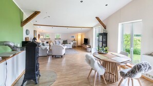 A spacious living area with a fireplace, a dining table with chairs, and a large window offering a view of the outdoors. - Holiday Apartment "Alter Heuboden" with Private Garden, Panoramic Views and Wi-Fi (Steinbergkirche)