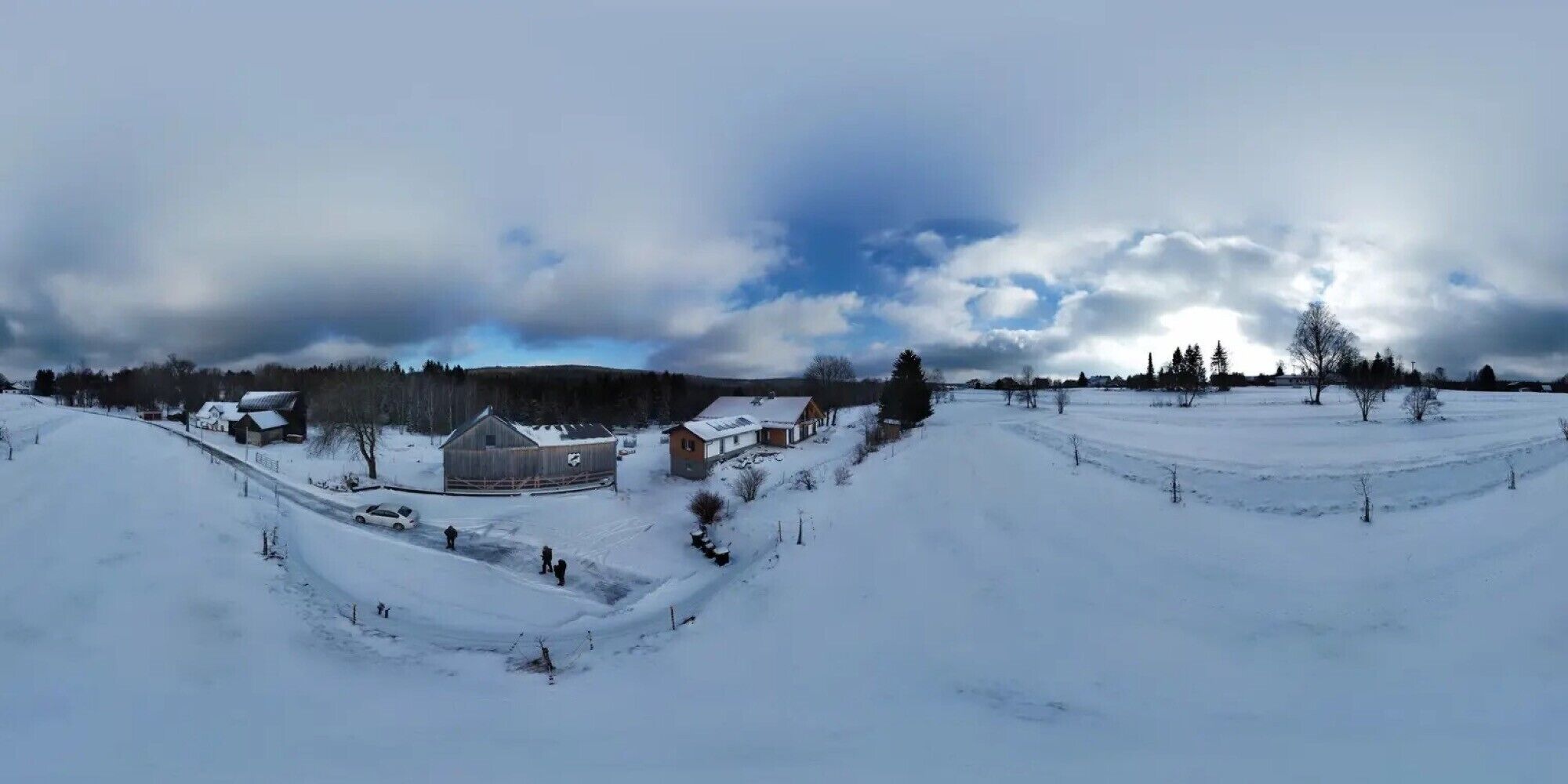 Eine ländliche Landschaft mit schneebedeckten Feldern, einem Holunder-Bauernhof und einigen Häusern.