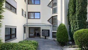 A modern building with a central entrance, multiple windows, and a well-maintained garden area. - Retreat Apartment with Mountain View, Balcony, and Wi-Fi (Langenargen)