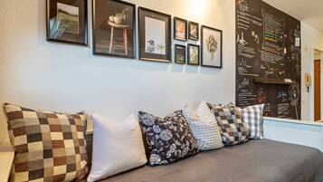 Una habitación con una cama, una pared decorada con marcos y una pizarra con escritura.