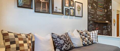 A room with a bed, a wall with framed pictures, and a chalkboard with writing.