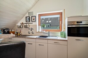 A modern kitchen with a window, stainless steel appliances, and a view of the outside. - Retreat Apartment with Mountain View, Balcony, and Wi-Fi (Langenargen)
