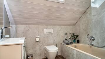 A modern bathroom with a toilet, sink, and bathtub.