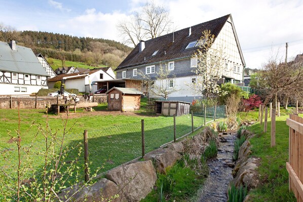 Un quartier résidentiel avec des maisons, un petit ruisseau et une cour clôturée.