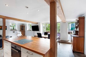 Une cuisine moderne dotée d’un plan de travail en bois, d’un four encastré et d’un coin repas avec une table et des chaises.