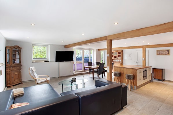 Un salon moderne avec un canapé, une table basse en verre et une table à manger en bois.