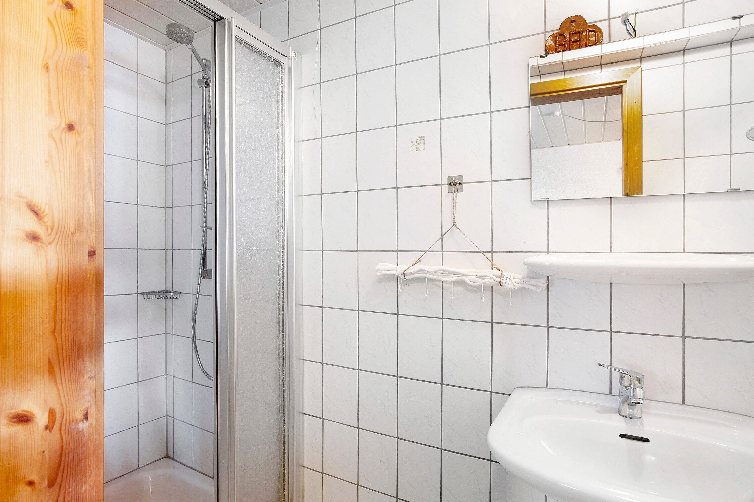 A bathroom with a shower, a sink, and a mirror.