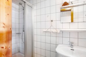 Une salle de bain avec une douche, un lavabo et un miroir.