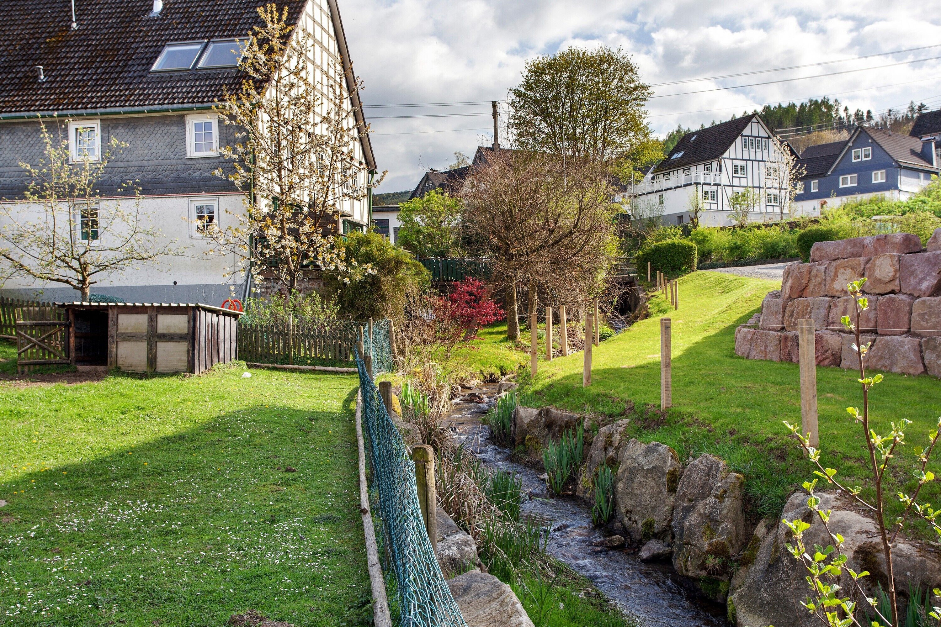 Un vecindario con casas, un jardín con un arroyo y una valla de madera.