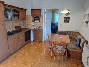 A kitchen with wooden cabinets, a dining table, and a sofa.