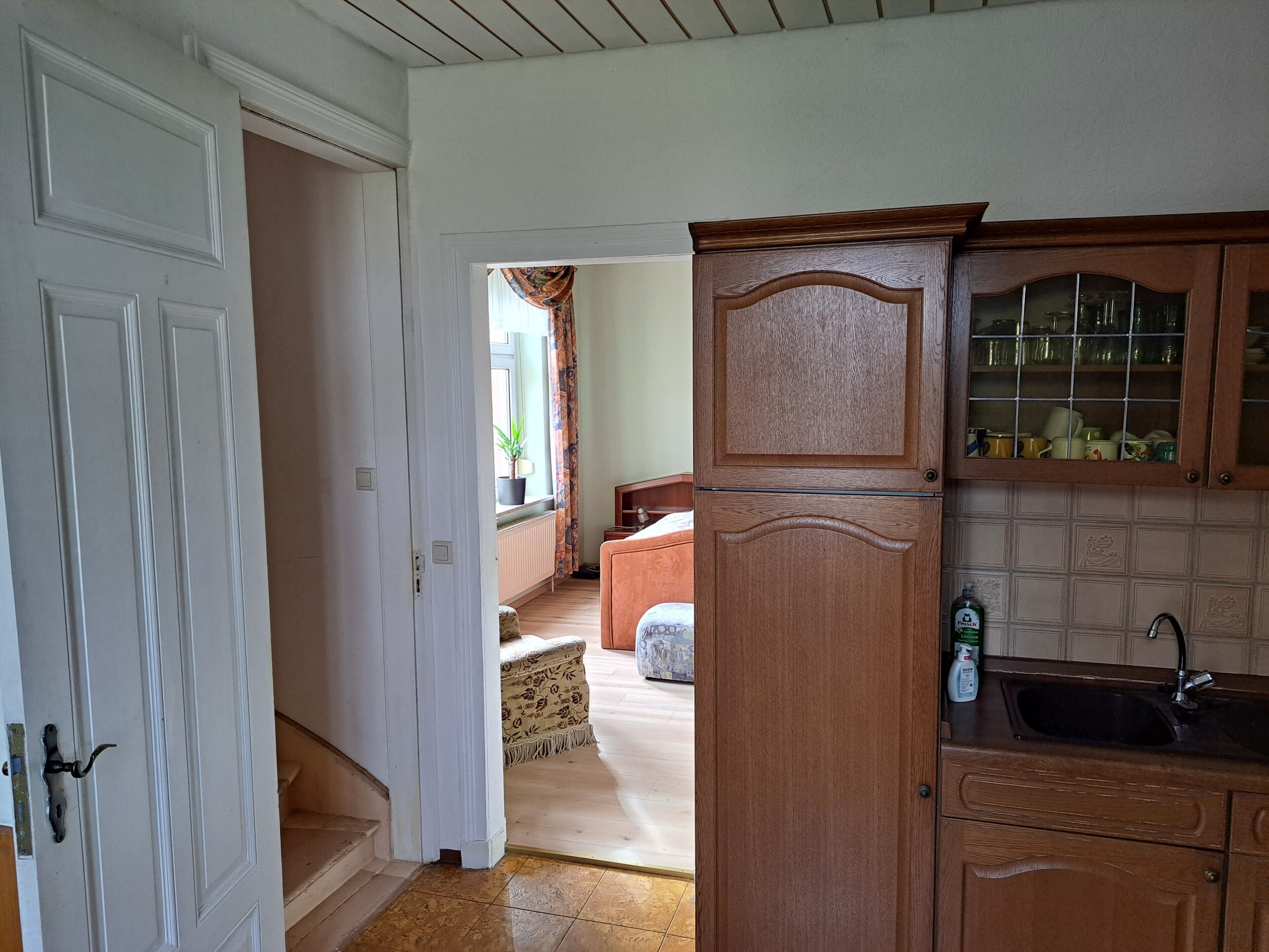 A room with a wooden cabinet, a white door, and a window with curtains.