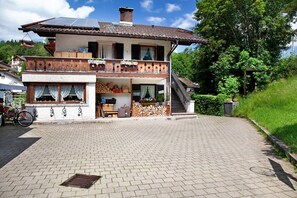 A two-story house with a balcony, a staircase, and a paved driveway.