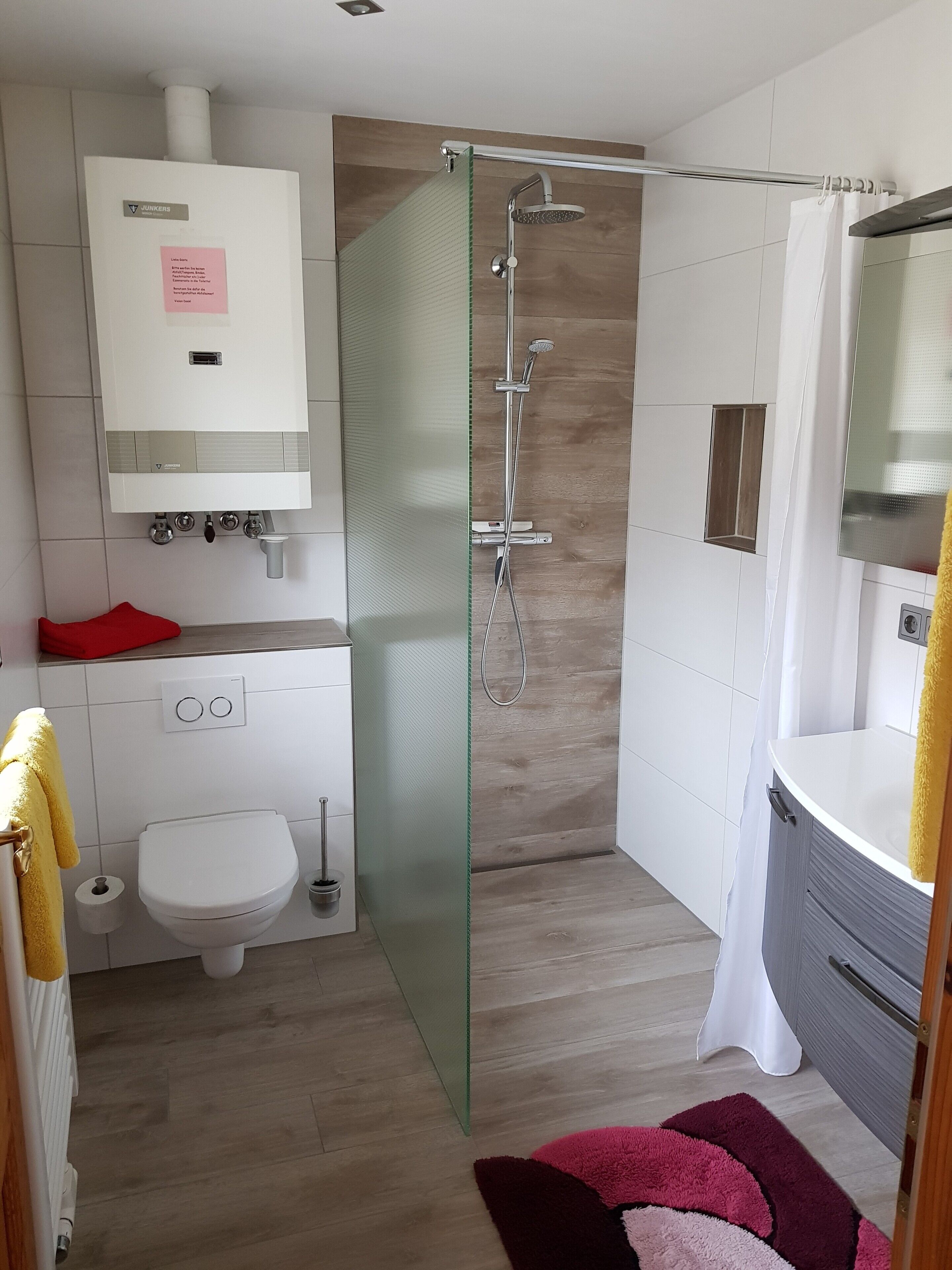 Ein modernes Badezimmer mit Glasdusche, Toilette und Waschbecken.