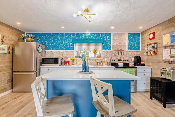 Una cocina moderna con una isla central, electrodomésticos de acero inoxidable y un salpicadero azul.