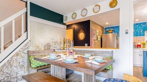 A dining area with a wooden table set for four, benches, and a blue floral ottoman. - Lake - King - Gym - Kayak - Fire Pit - PetsOK - WD (Ashford)