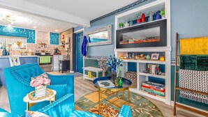 A modern living room with a blue sofa, a round coffee table, and a bookshelf. - Lake - King - Gym - Kayak - Fire Pit - PetsOK - WD (Ashford)