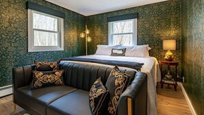 A bedroom with a bed, a black leather sofa, and a nightstand with a lamp. - Lake - King - Gym - Kayak - Fire Pit - PetsOK - WD (Ashford)