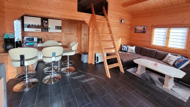 Un interior acogedor de cabaña con comedor, sofá, escalera y cocina.