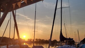Un puerto deportivo con barcos amarrados, un atardecer de fondo y cielo despejado.