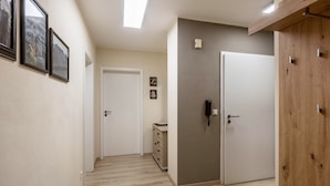 Un pasillo con suelo de madera, una puerta blanca, un armario de madera y un mueble pequeño.