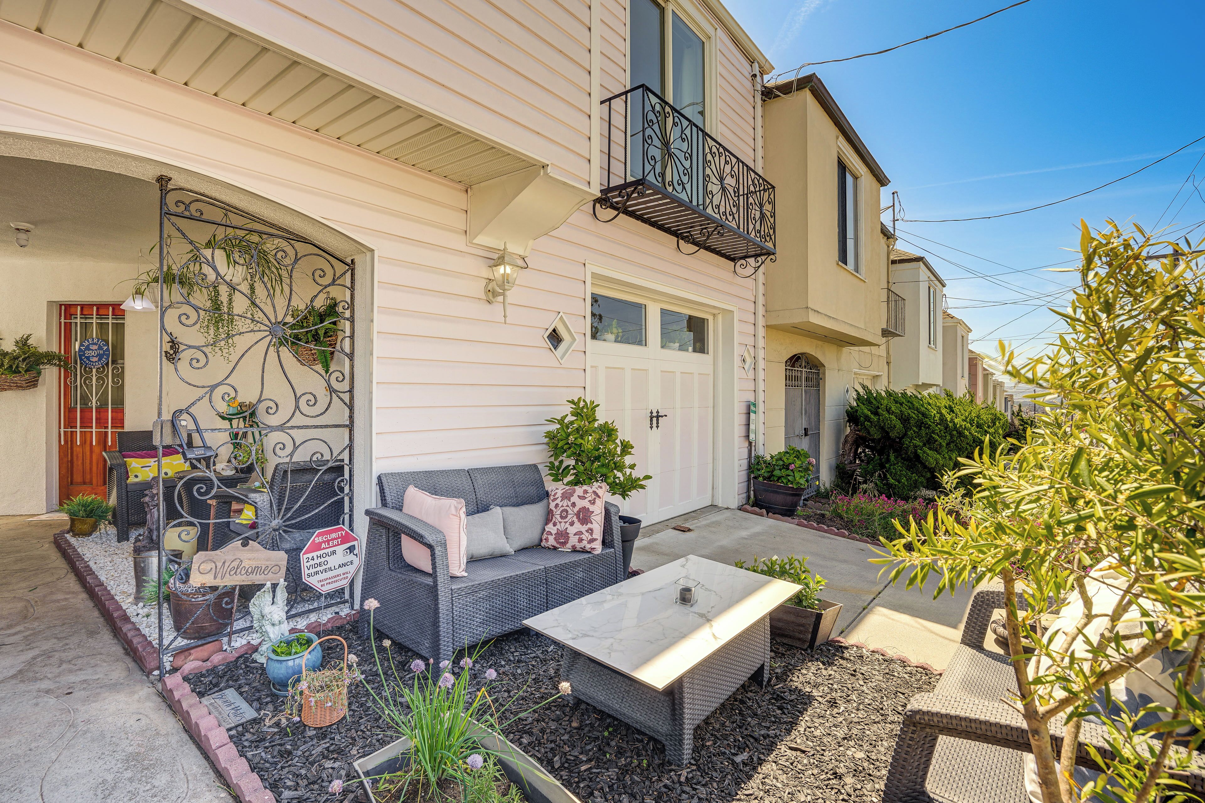 A residential property with a patio, outdoor furniture, and a security sign.