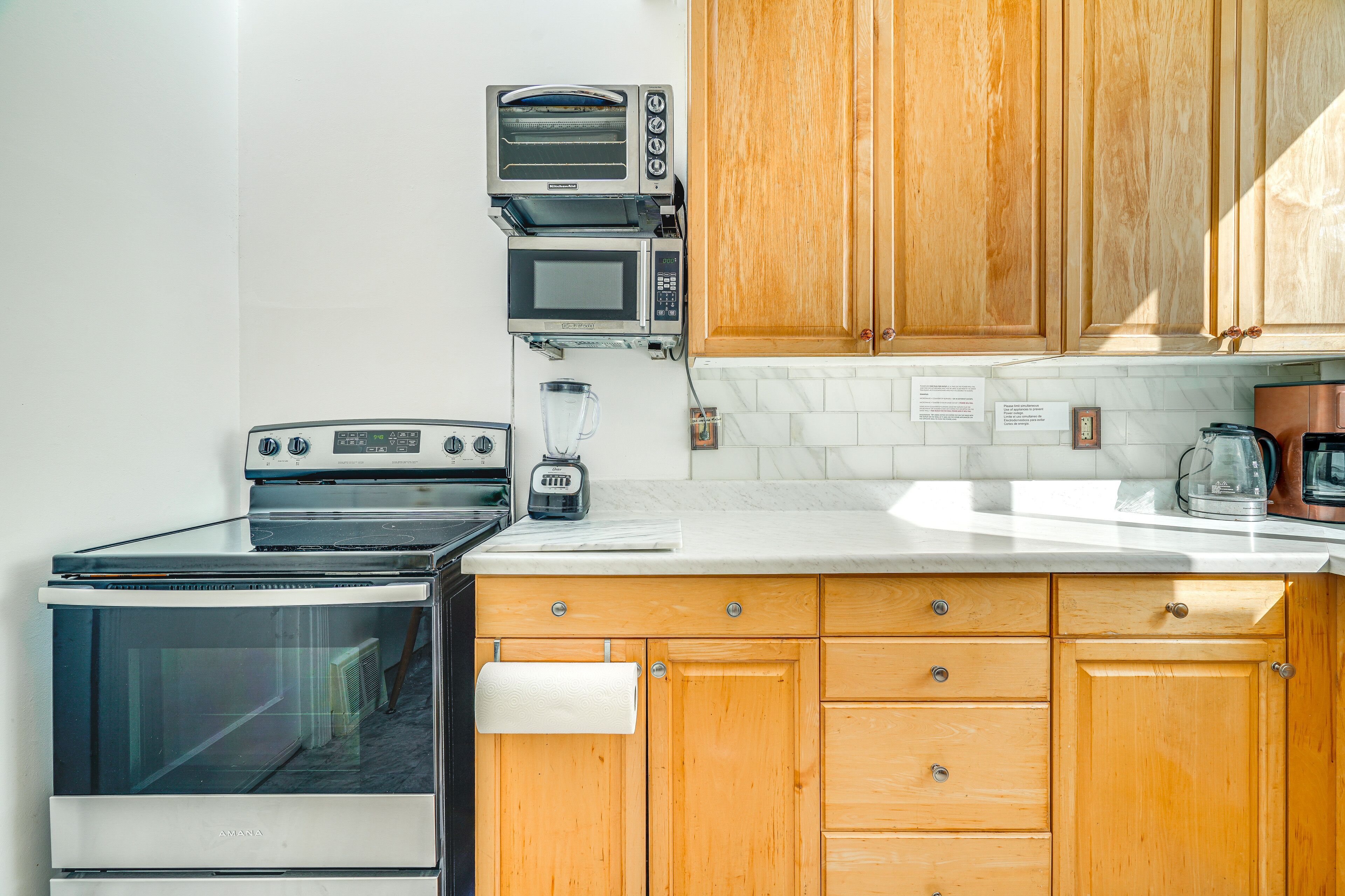 Una cocina con armarios de madera, horno empotrado, microondas y cafetera.