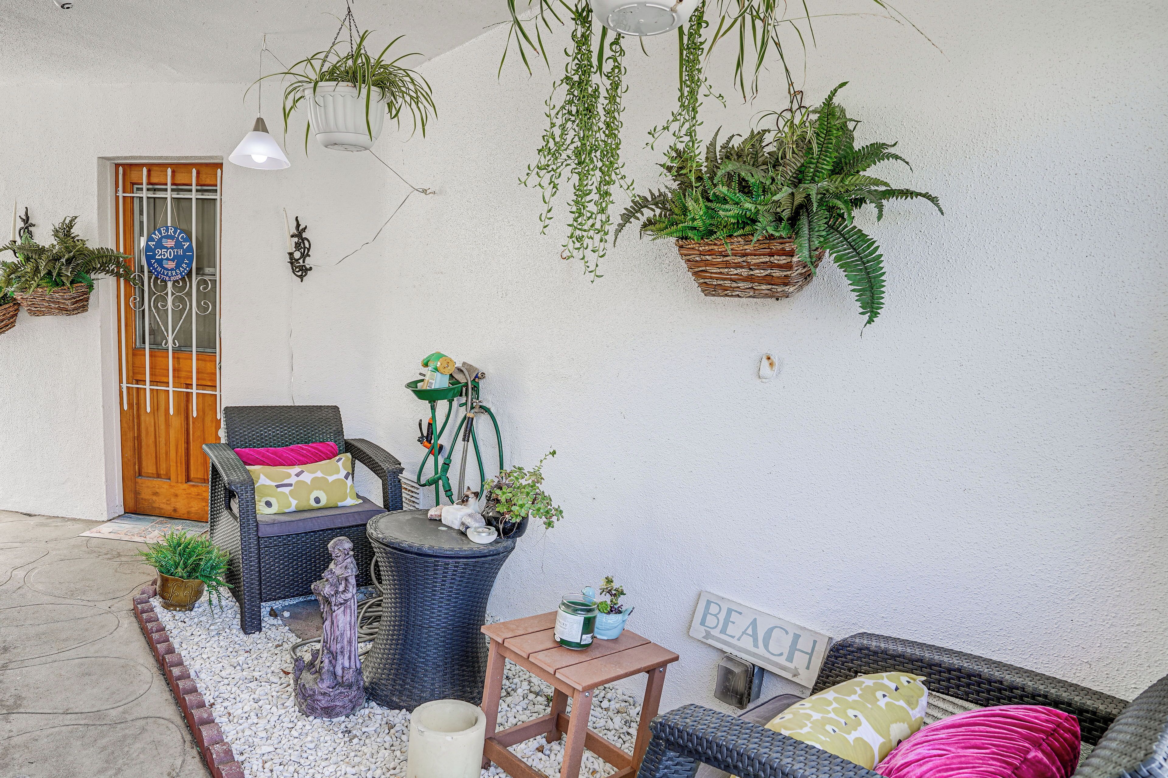 A porch with wicker furniture, hanging plants, and a 'BEACH' sign.