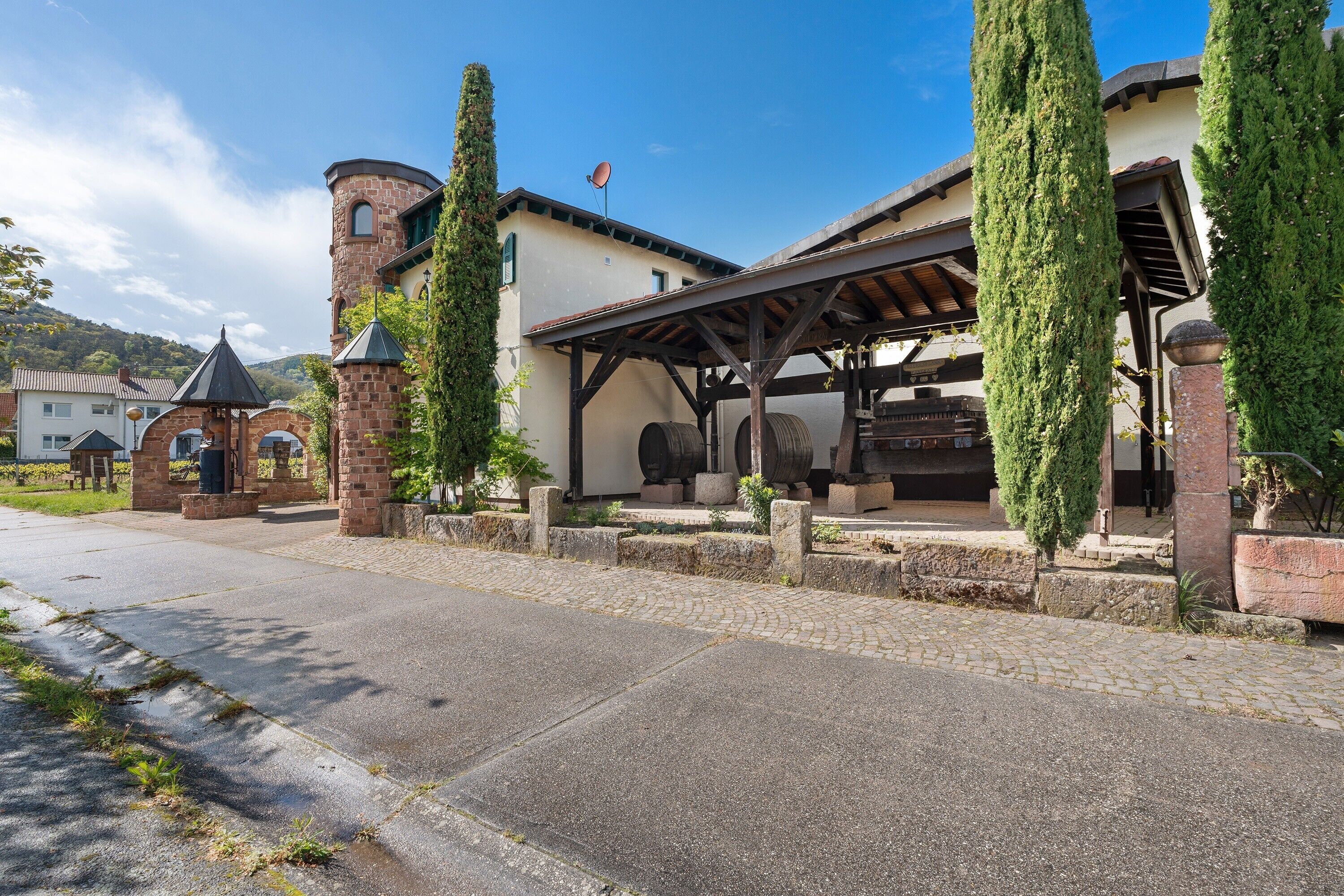 Un bâtiment doté d’une tour, d’un patio couvert et de grands arbres.