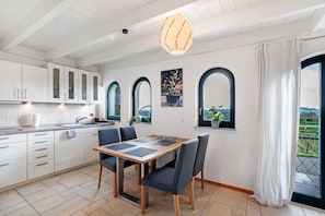 Une cuisine moderne avec des meubles blancs, une table à manger en bois et une vue par la fenêtre.