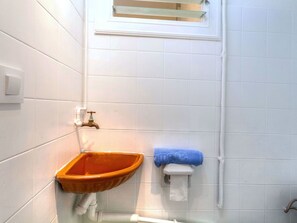 A bathroom with white tiled walls, a wooden sink, a towel rack with a blue towel, and a window above the sink. - Nice apartment for 4 guests with A/C, TV and terrace (Llançà)