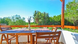 A wooden table and chairs under a pergola with a view of trees and a clear sky. - Nice apartment for 3 people with WIFI, A/C, TV and terrace (Zadar)
