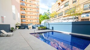 A swimming pool with a tiled deck, lounge chairs, and potted plants. - Nice apartment for 4 guests with pool, A/C, TV and terrace (Calpe)
