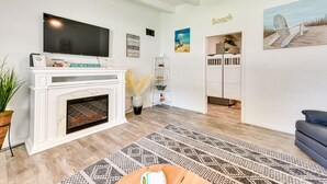 A living room with a fireplace, a flat-screen TV, and beach-themed decorations. - Cozy Fort Walton Beach Escape w/ Private Patio! (Fort Walton Beach)
