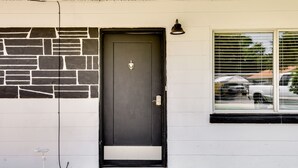 A black door with a stone wall, a welcome mat, and a window with blinds. - Cozy Fort Walton Beach Escape w/ Private Patio! (Fort Walton Beach)