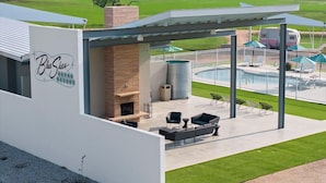 A modern building with a patio area, outdoor seating, and a pool. - Blue Skies Resort / Glamping / Pool / Fireplace (Willow City)