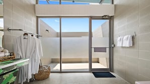 A modern bathroom with a glass door leading to an outdoor area, a towel rack, and a counter with a basket. - Blue Skies Resort / Glamping / Pool / Fireplace (Willow City)