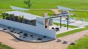 A modern building with a pool, outdoor seating, and a view of the surrounding countryside.