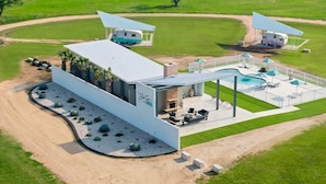 Una casa moderna con un patio, una piscina y una caravana.