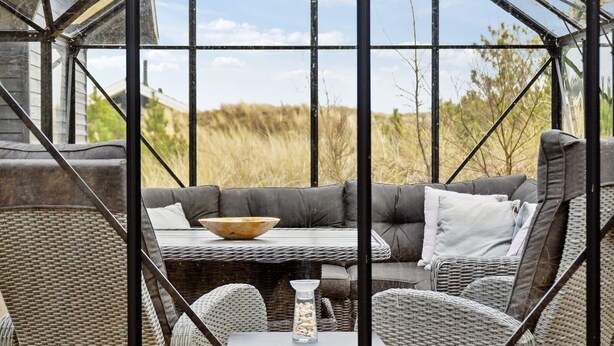 Une pièce de style serre avec un coin salon doté de sièges confortables, une petite table et un bol.