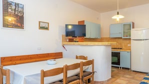 Eine kleine Küche mit Essbereich, Fernseher und Kühlschrank.