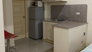 A compact kitchen with a refrigerator, microwave, and sink. - Rovimar Condo Angeles  (Angeles City)