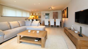 Ein modernes Wohnzimmer mit einem Ecksofa, einem Holztisch und einem Fernseher an der Wand.