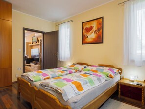 A bedroom with a bed, a nightstand, a wooden wardrobe, a door leading to another room, and a painting on the wall. - Lovely apartment for 6 people with A/C, WIFI, TV and terrace (Balatonfüred)