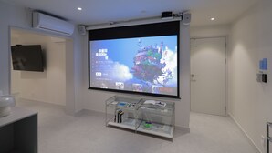 Une chambre moderne avec un grand téléviseur à écran plat fixé au mur, une vitrine contenant des livres et une porte visible au fond.