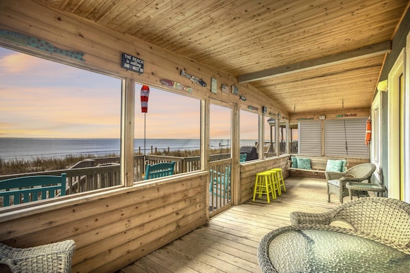 Relax on the deck with wicker chairs and a bench, taking in the view of the beach and ocean.